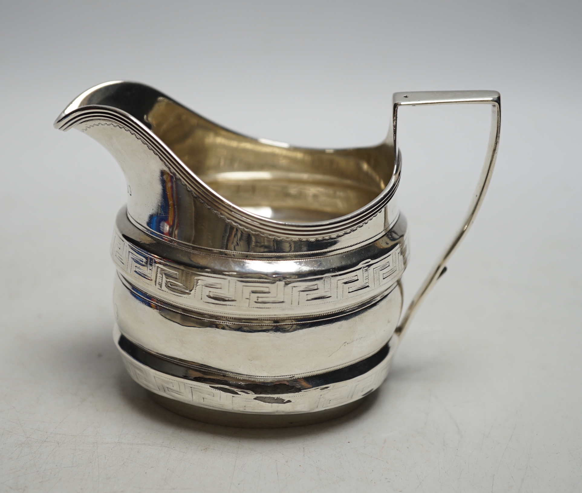 A George III silver helmet shaped cream jug, with engraved key pattern band, London 1804, 9cm. (a.f.)